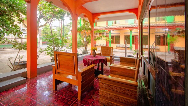 A covered outdoor seating area with wooden furniture and a tiled floor.