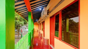 A corridor with a red-tiled floor, green and red walls, and a ceiling with exposed beams.