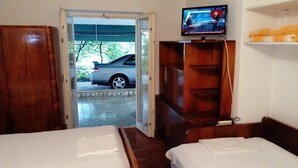 A hotel room with two beds, a television mounted on the wall, and a view of a parked car outside. - Apartment Neno (Crikvenica)