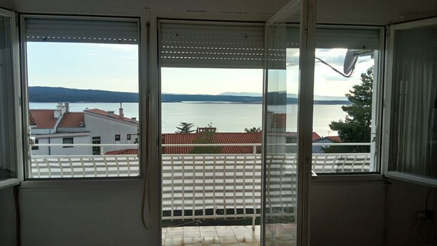 A room with a view of a lake and distant mountains through large windows. - Apartment Neno (Crikvenica)