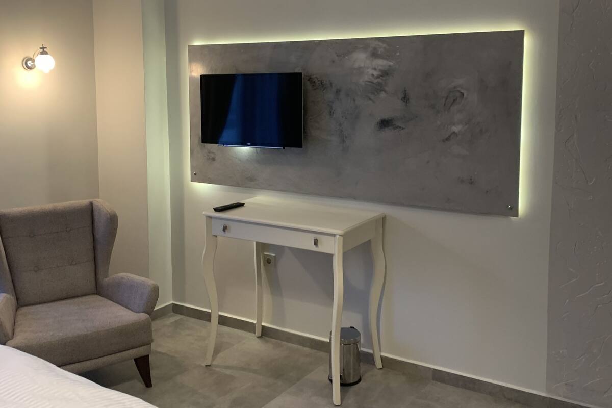 Une chambre à coucher moderne, équipée d’un lit, d’un bureau et d  ’un téléviseur fixé au mur.