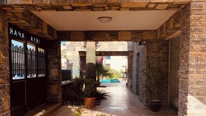 A stone-walled corridor with a pool in the background, potted plants, and a door labeled "CRAZY". - Orya Apart (Bodrum)