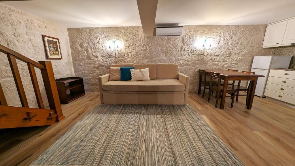 Una sala de estar acogedora con un sofá, una mesa de comedor y una cocina con armarios y un refrigerador.
