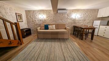 Una sala de estar acogedora con un sofá, una mesa de comedor y una cocina con armarios y un refrigerador.