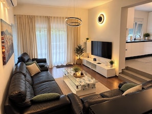A modern living room with a leather sofa, a coffee table, and a flat-screen TV. - Apartment Barbara (Crikvenica)