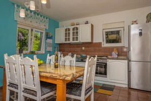 A kitchen with white cabinets, a stainless steel refrigerator, and a dining table with chairs. - Apartment Barbara (Crikvenica)