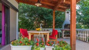 Un patio al aire libre con una mesa redonda y sillas, rodeado de plantas en macetas.