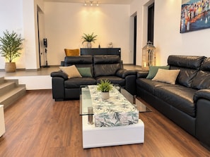 A modern living room with a sectional sofa, a glass coffee table, and a painting on the wall. - Apartment Barbara (Crikvenica)