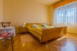 Ein Schlafzimmer mit einem hölzernen Bett, einem Nachttisch, einer Lampe, einem Sessel und einem Tisch mit Spitze.