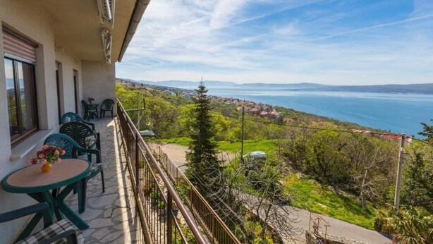 A balcony with a view of a coastal landscape, including a body of water and distant hills. - Apartment Ivka (Crikvenica)