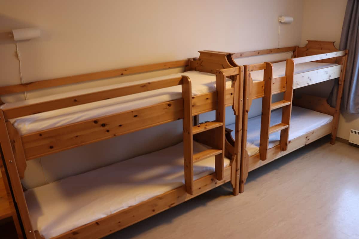 A bunk bed with wooden frames and white bedding.