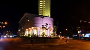 Un hotel con una torre destacada y un edificio circular con ventanas iluminadas.