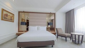 Habitación de hotel con una cama grande, una silla, una mesita y un espejo.