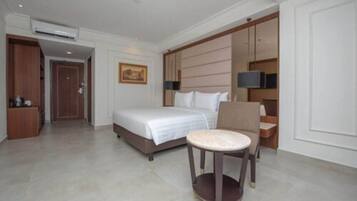 A hotel room with a bed, a round table, a chair, a TV, and a wardrobe.