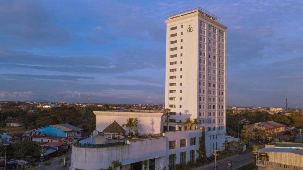 Um hotel alto e retangular, com telhado plano e entrada central.