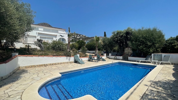 A swimming pool with a stone border, surrounded by lounge chairs and greenery. - Ref. Mur16 -  (Rosas / Roses)