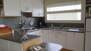 A kitchen with white cabinets, a granite countertop, a stove, a sink, and a window with blinds. - Ref. Mur16 -  (Rosas / Roses)