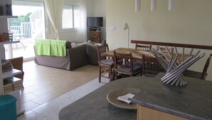 A modern living room with a sofa, a dining table, and a TV. - Ref. Mur16 -  (Rosas / Roses)