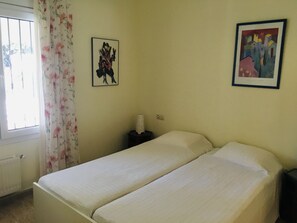 A room with a bed, a window with curtains, and two framed artworks on the wall. - Ref. Nav51 -  (Rosas / Roses)