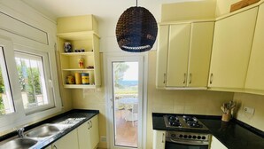 A kitchen with white cabinets, a black countertop, a stove, and a sink. - Ref. Nav51 -  (Rosas / Roses)