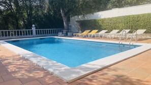 A rectangular swimming pool with a tiled edge, surrounded by a tiled deck.