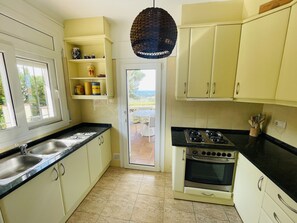 A kitchen with a gas stove, a sink, and a window.