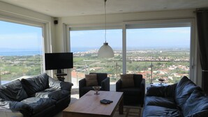 Un ampio soggiorno con una grande finestra che si affaccia sulla città, una TV a schermo piatto e divani in pelle.