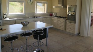 Una cucina moderna con isola centrale, sgabelli da bar, piano cottura, forno e un orologio a parete.