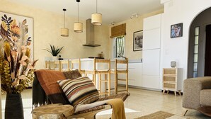 A living room with a wooden chair, a sofa, and a dining area with chairs and a table. - Ref. Leo06 -  (Rosas / Roses)