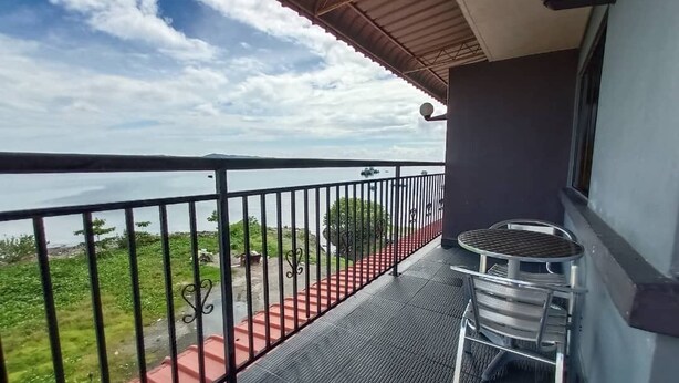 Un balcón con barandilla metálica, una mesita y una silla.