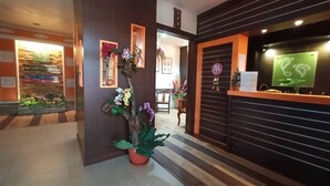 Un área de recepción con un mostrador de madera, una planta en maceta y un cuadro en la pared.