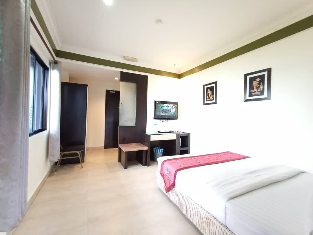 Una habitación de hotel con una cama, un escritorio, un televisor y una puerta que da a otra habitación.