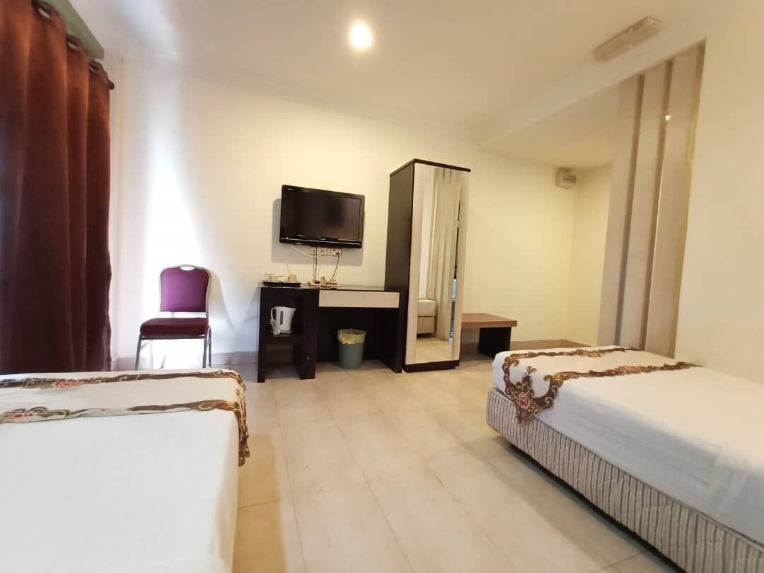 A hotel room with two beds, a desk, a chair, a television, and a wardrobe.