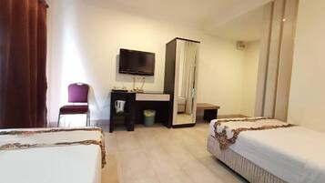 A hotel room with two beds, a desk, a chair, a television, and a wardrobe.