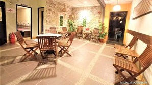 Un comedor con mesas y sillas de madera, una pared de piedra y plantas en macetas.