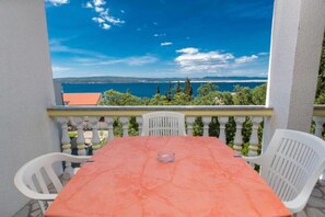 Ein Balkon mit Tisch und Stühlen, mit Blick auf ein Gewässer und Grünflächen.