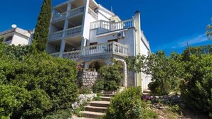 Un edificio de varios pisos con balcones, rodeado de vegetación.