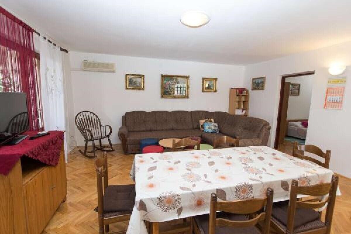 Un coin repas avec une table dressée pour quatre personnes, un canapé, un fauteuil à bascule et un buffet en bois.