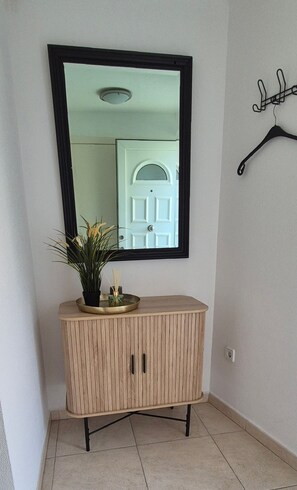 Comfortable corner room with a light-colored floor, wooden cabinet, and a large mirror.