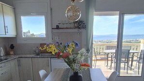 Ein Essbereich mit Tisch für sechs Personen, eine Küche mit Fenster und ein Balkon mit Blick.