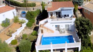 Ein zweistöckiges Haus mit Swimmingpool, Balkon und Garten.