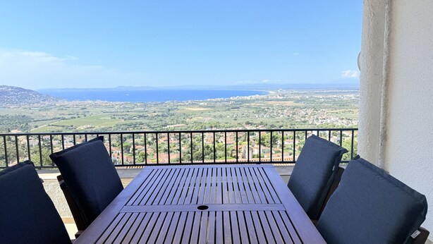 Un balcon avec une table et des chaises, offrant une vue sur un paysage côtier.
