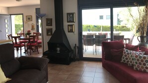 En stue med pejs, spiseplads og store skydedøre ud til en udendørs terrasse.