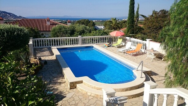 A rectangular swimming pool with a white balustrade, surrounded by stone tiles and lush greenery. - Ref. And28 -  (Rosas / Roses)