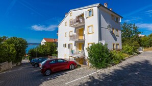 Un immeuble à plusieurs étages doté de balcons, d’un espace de stationnement et offrant une vue sur la mer.