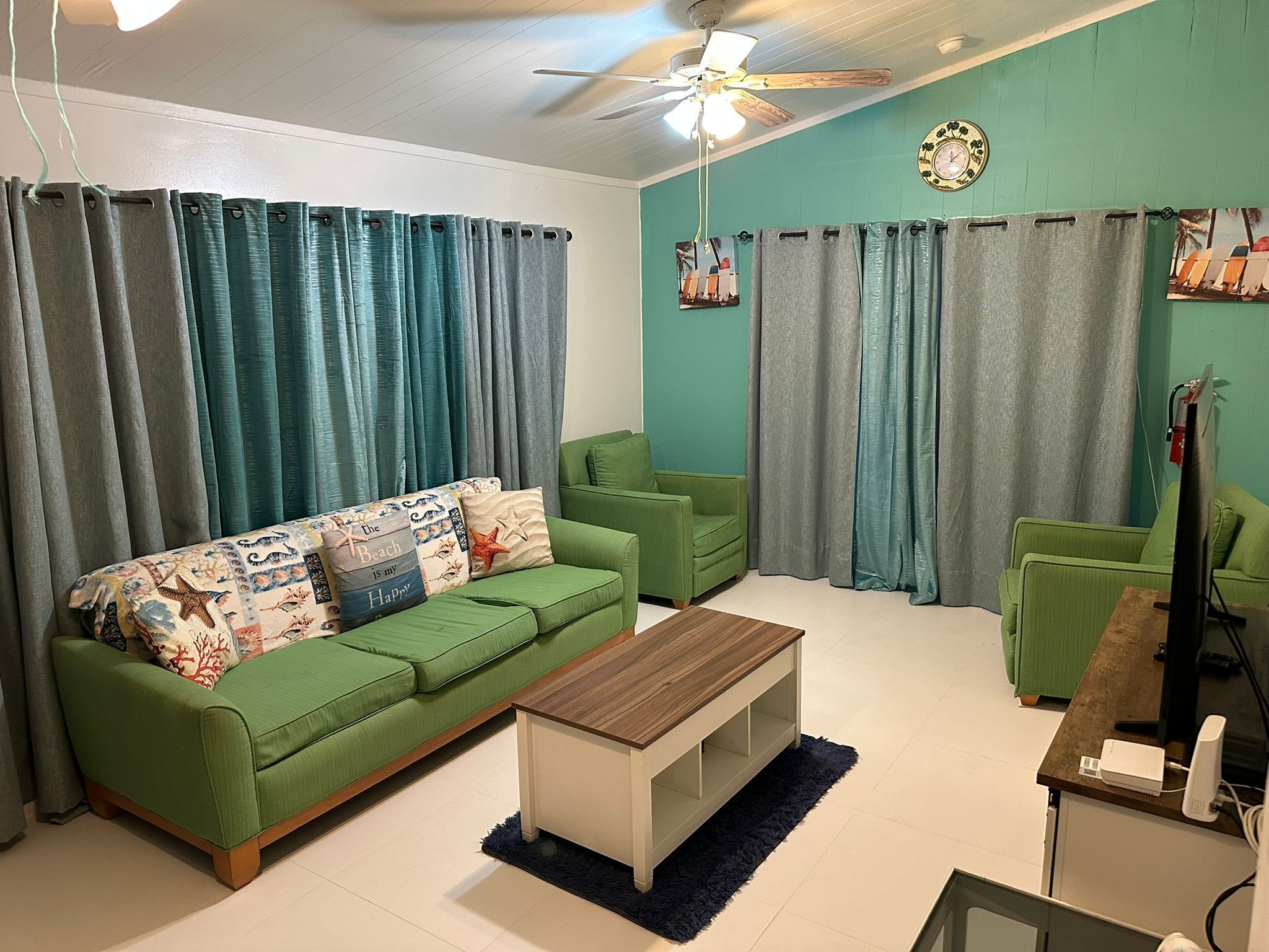 Ein Wohnzimmer mit einem grünen Sofa, einem Holztisch und einem Deckenventilator.