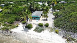 A beachfront property with a turquoise building, palm trees, and a sandy beach.