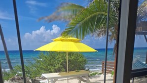 A beach view with a yellow umbrella, a wooden bench, and a table.