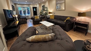 Uma sala de estar moderna com sofá, poltrona, mesa de centro e TV.