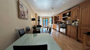Uma cozinha moderna com armários de madeira, um espaço de refeições com mesa de vidro e vista para o exterior.